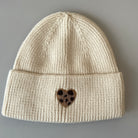springstar strickmütze damen beanie mit herz mütze mit patch im leo look herzmotiv leo herz patch reitsport und freizeit beanie warme mütze verschiedene farben kuscheliger beanie mit aufnäher creme weiß
